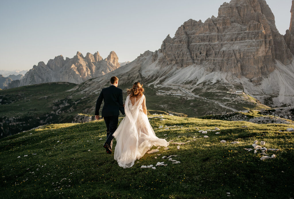 Bride and groom walking in mountain landscape.