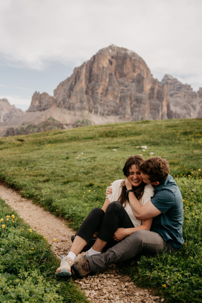 Couple sitting on mountain path, enjoying nature together.