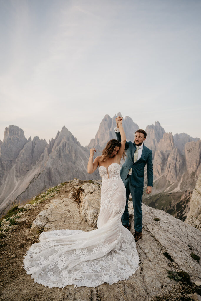 Couple dances on mountain in wedding attire