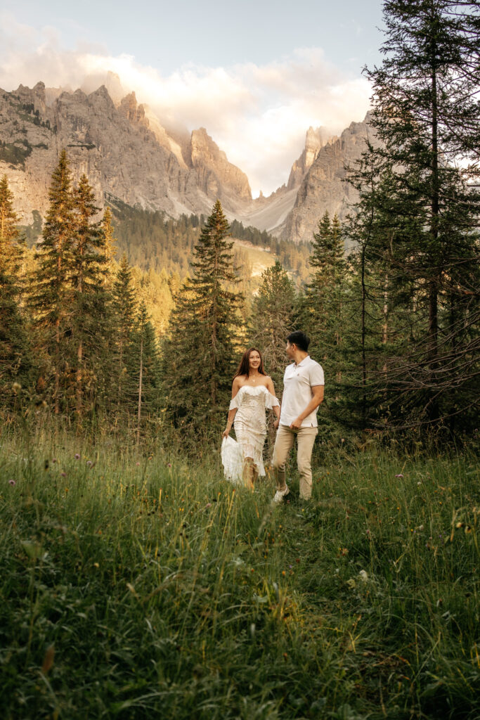 Couple walking in forest with mountain backdrop.