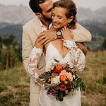 Couple embracing with wedding bouquet outdoors.