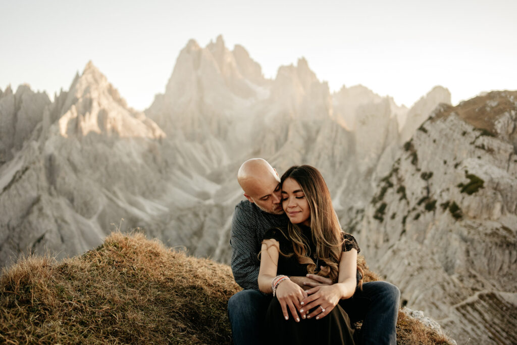 Couple sitting lovingly in mountain landscape.