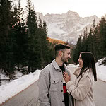 Couple smiling in snowy mountain landscape.