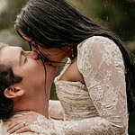 Couple kissing in wedding attire outside.