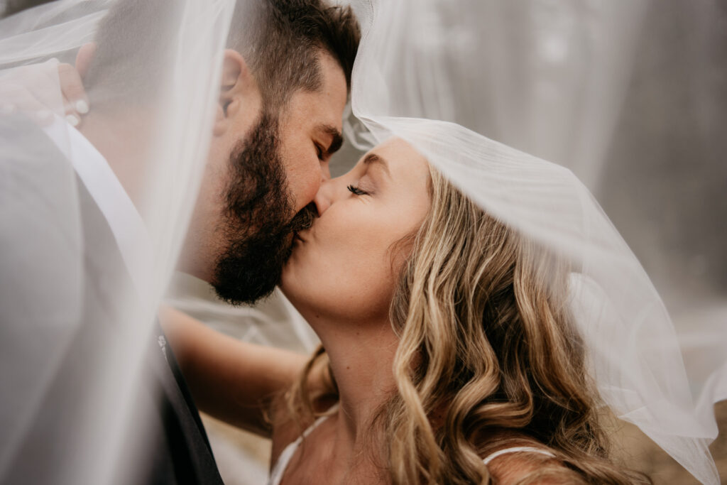 Bride and groom kissing under veil