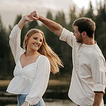 Couple dancing outdoors near a lake and forest.