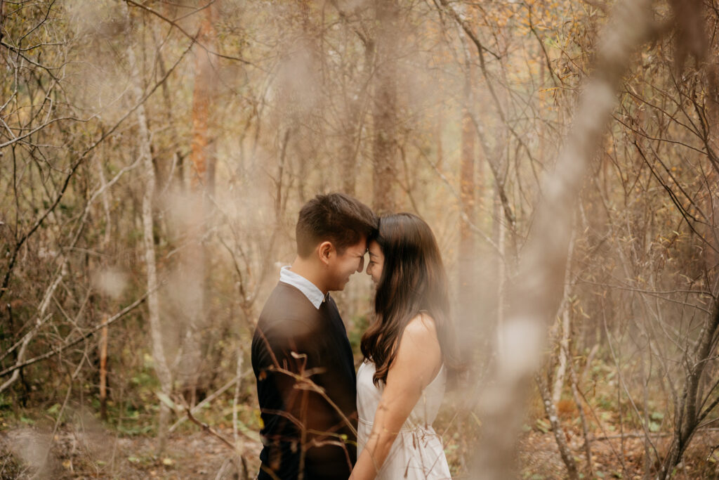 Couple embracing in a serene forest setting.