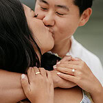 Couple kissing, engagement ring visible.