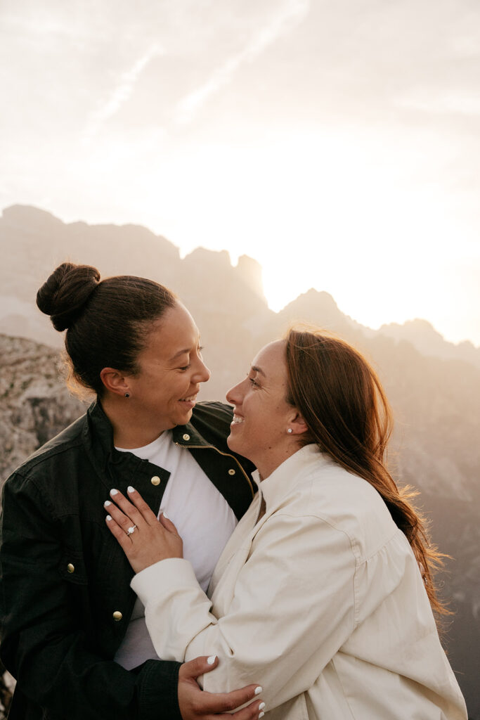 Couple embraces at sunset with mountain backdrop.