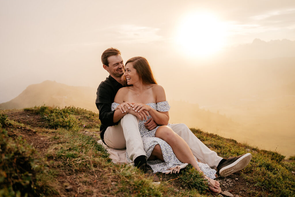 Couple sitting on hill during sunset.