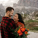 Couple laughing in mountain scenery with flowers.