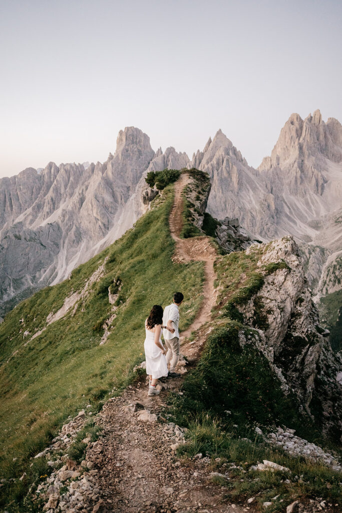 Couple walking on mountain trail with stunning view.