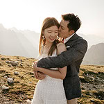 Couple embraces in scenic mountain landscape.