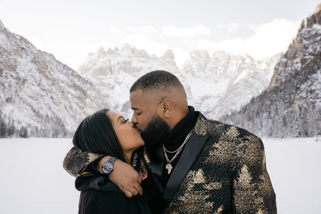 Couple kissing in snowy mountain landscape.