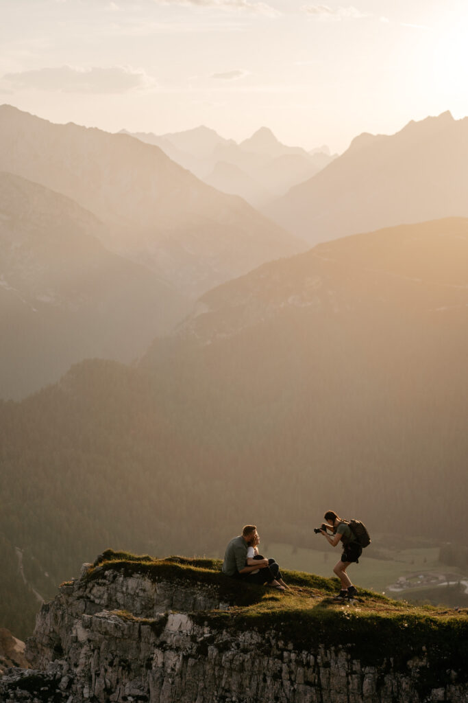 Photographer captures couple on mountain at sunset.