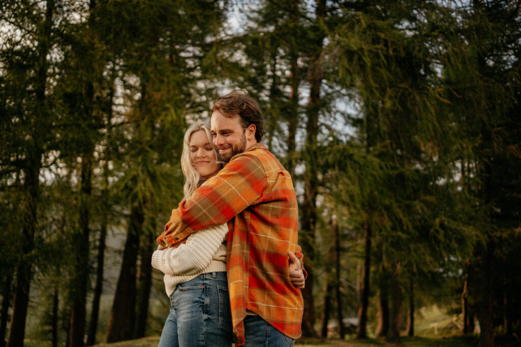 Couple hugging in forested area, autumn setting.