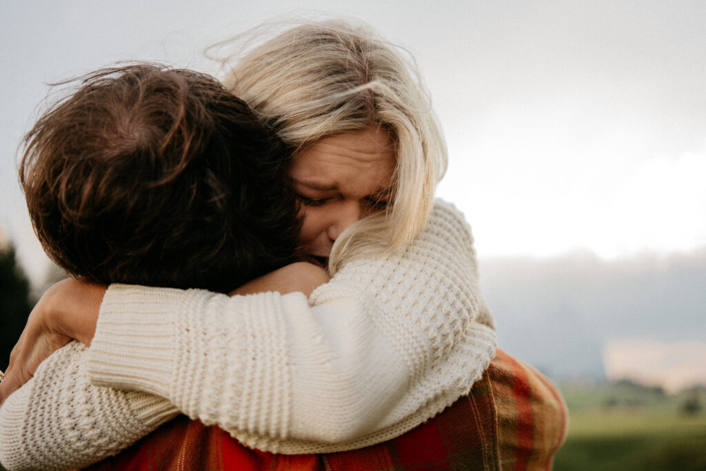 Two people hugging closely outdoors.
