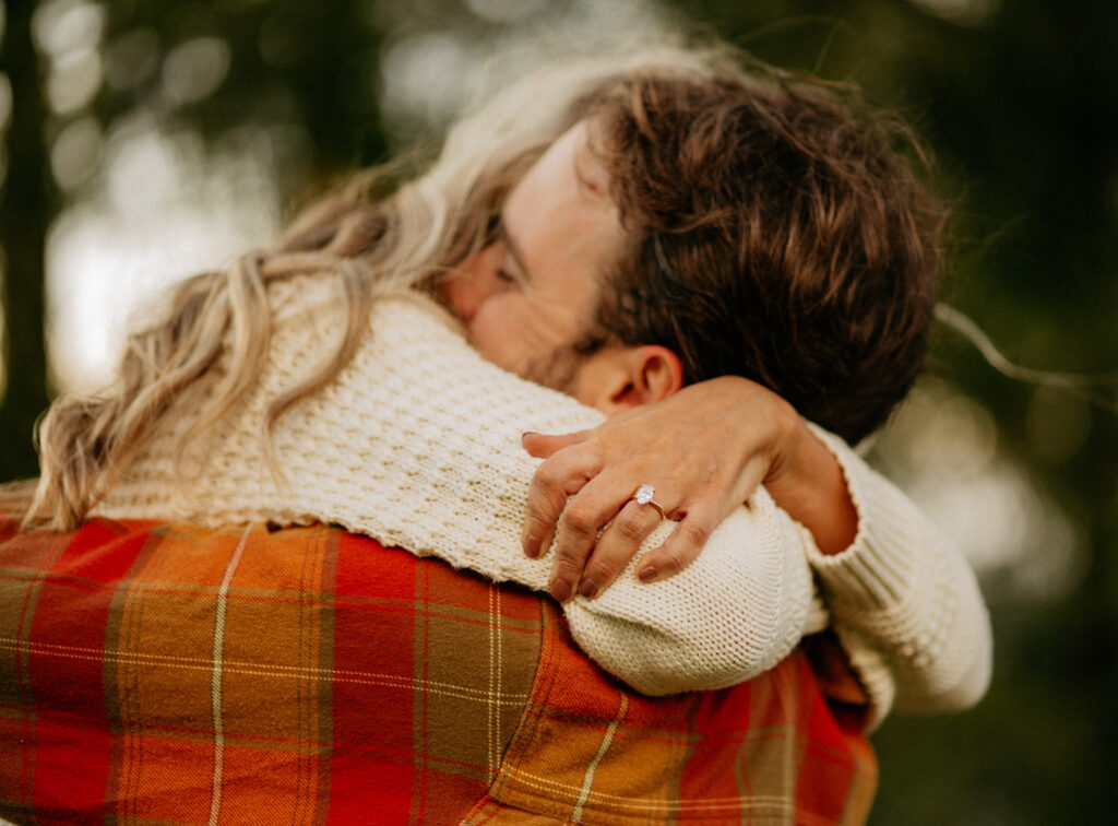 Couple hugging, woman wearing engagement ring.