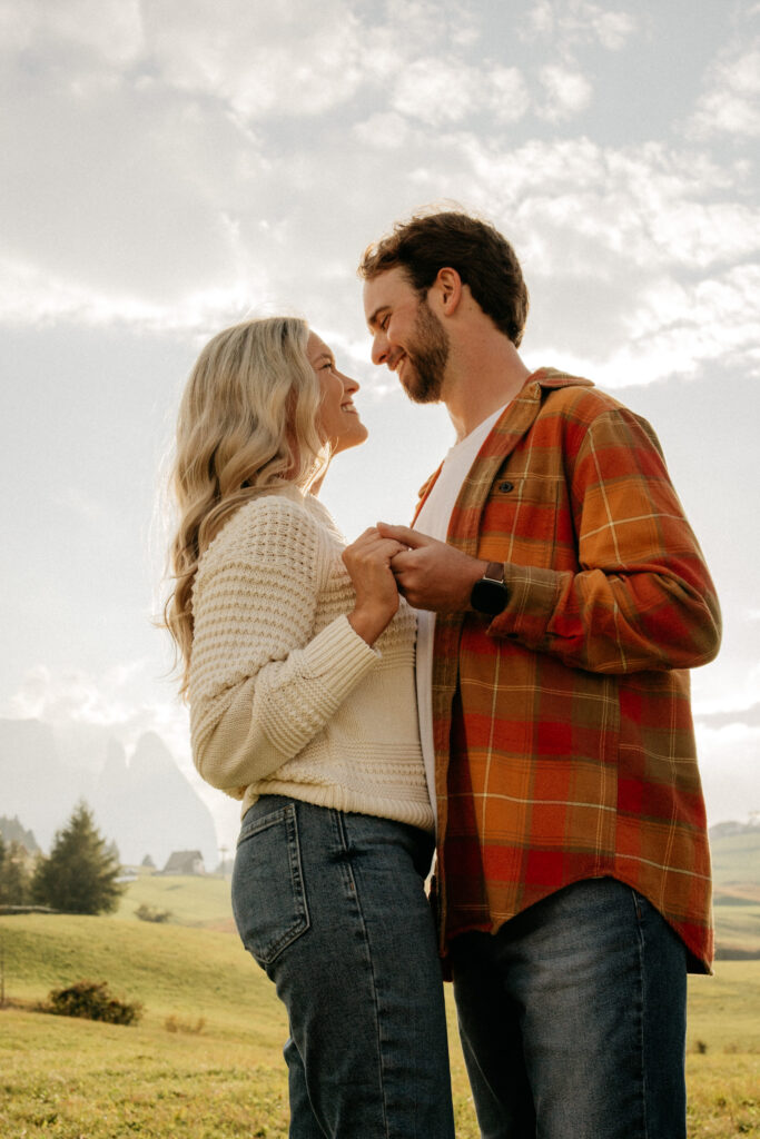 Couple smiling at each other outdoors in sunlight.