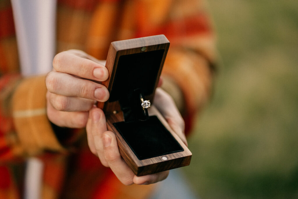 Person holding engagement ring in wooden box
