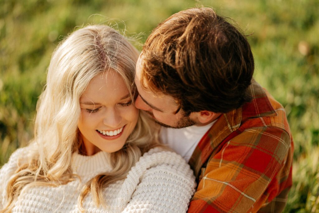 Smiling couple sitting in a sunny field.