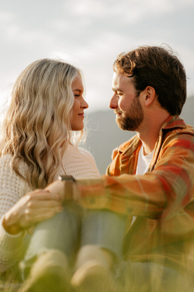 Couple sitting together outdoors, facing each other.