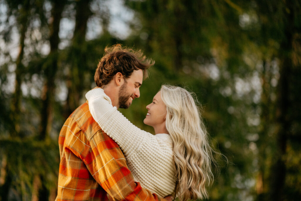 Couple hugging outdoors, smiling in nature.