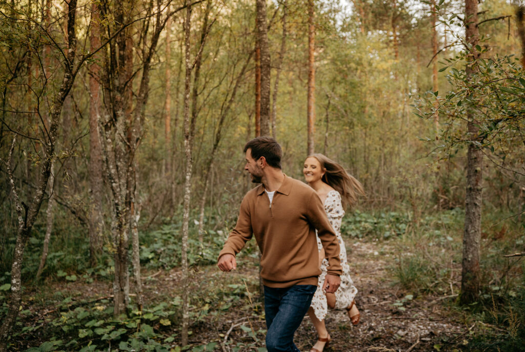 Couple joyfully running through forest path