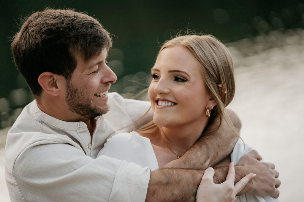 Smiling couple embracing by the water