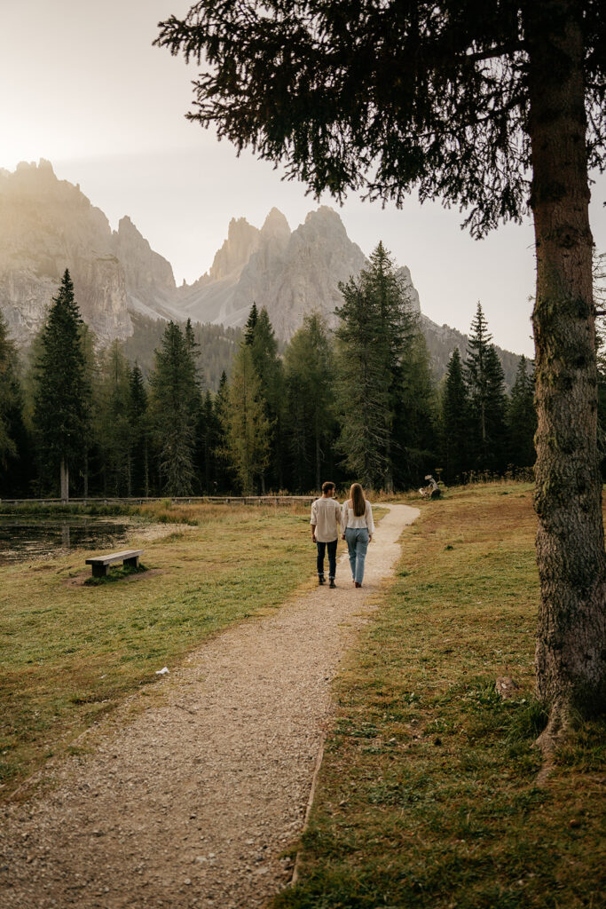 Couple walking on forest path towards mountains.