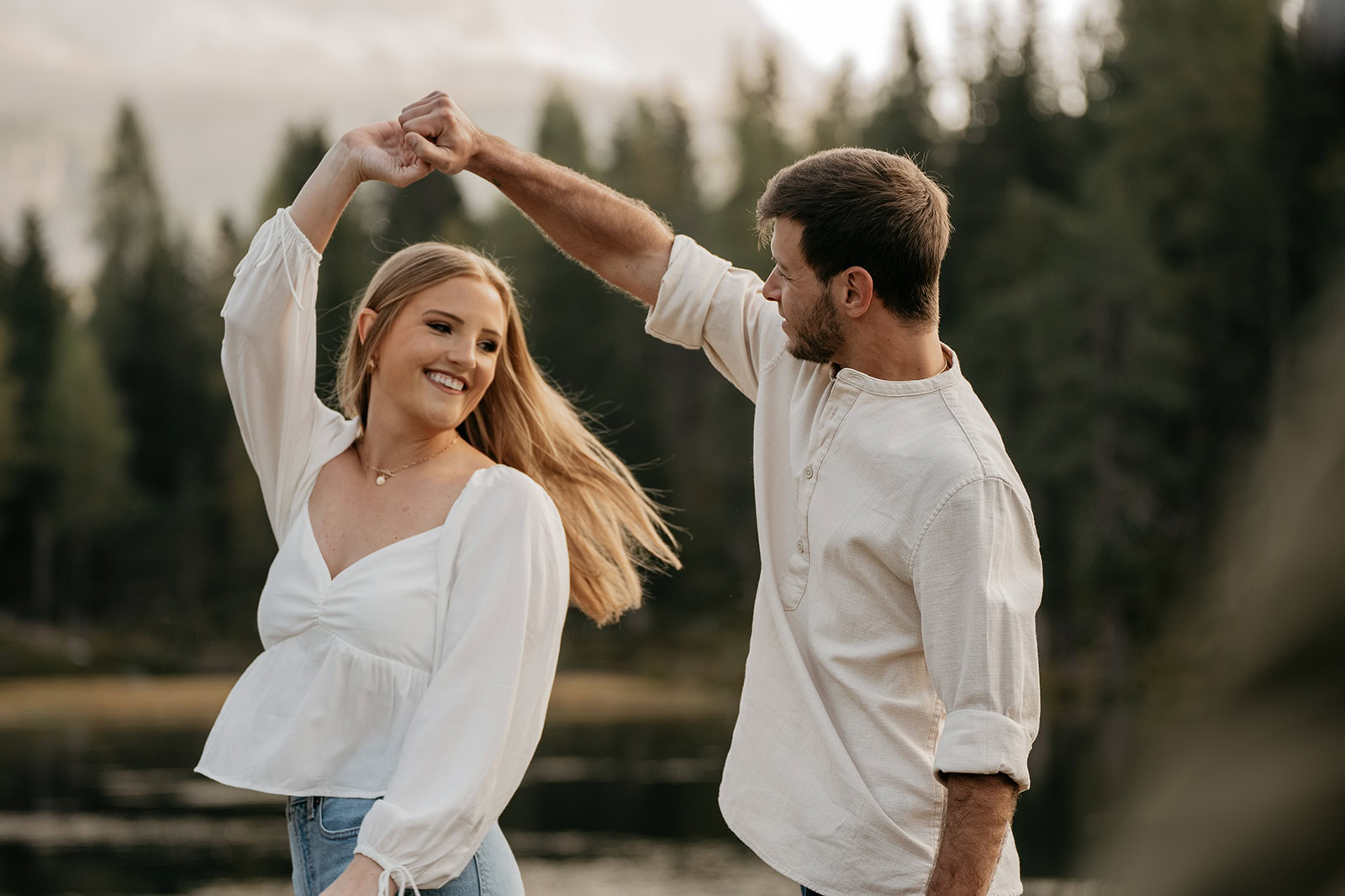 Couple dancing together outdoors near forest.