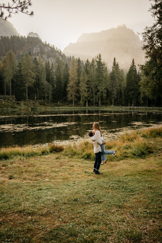 Couple embracing by a tranquil forest lake.