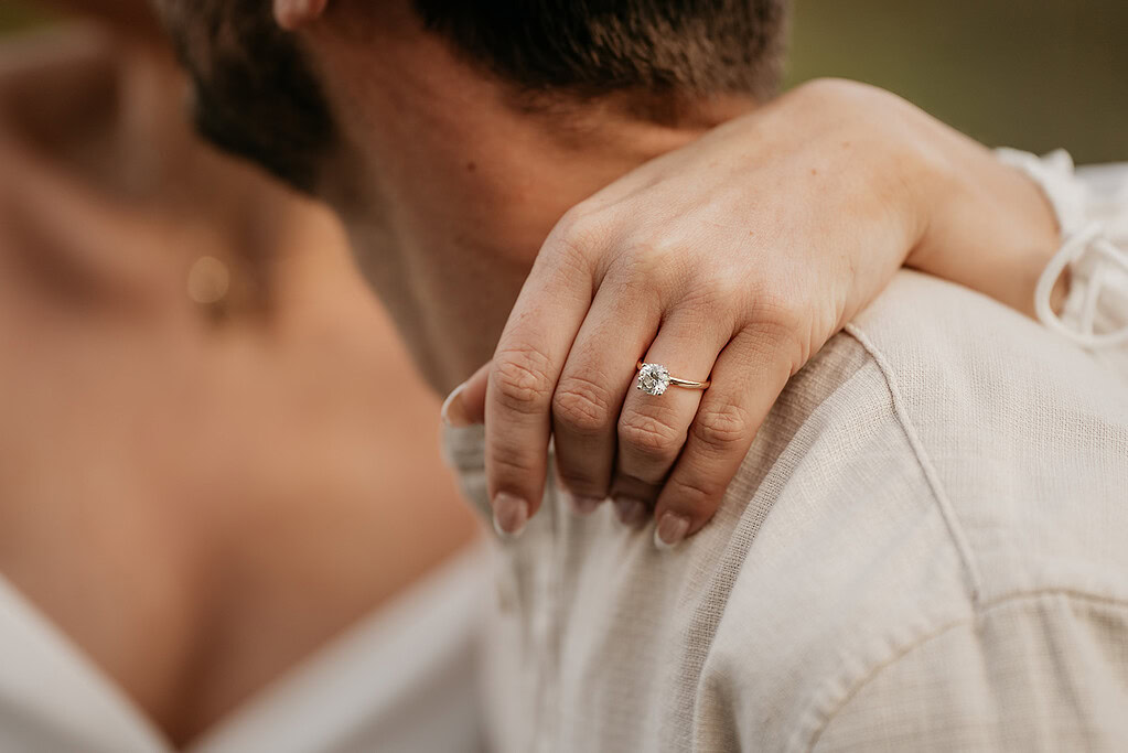 Hand with engagement ring on shoulder