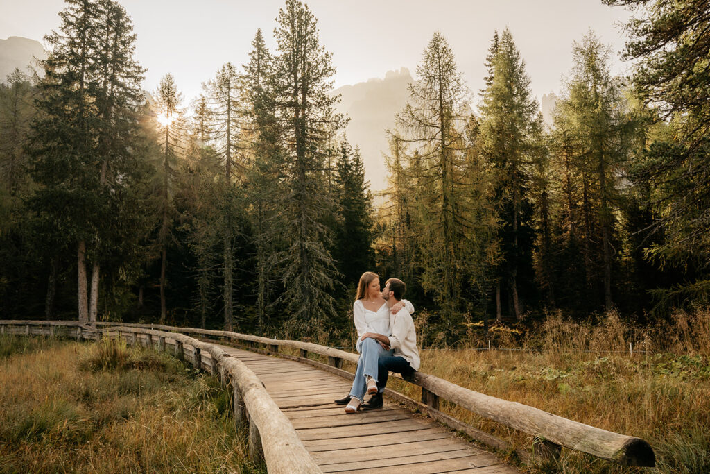 Couple sitting on wooden path in forest.