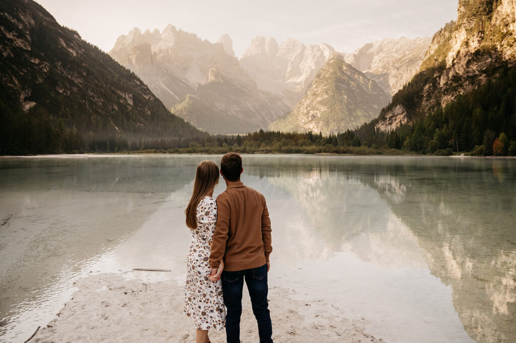 Couple admiring serene lake and mountain view.