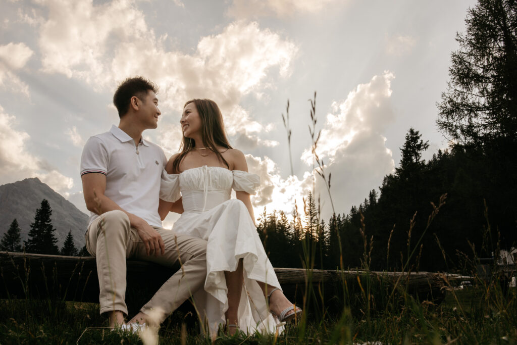 Couple sitting on wooden log at sunset