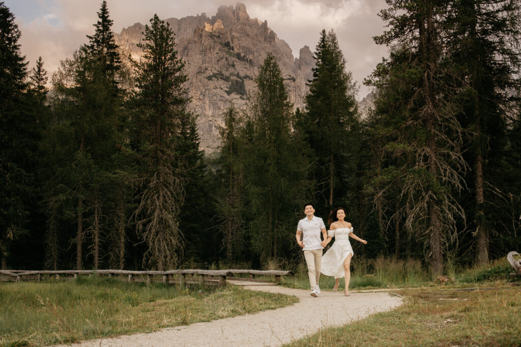 Couple running on forest trail near mountains.