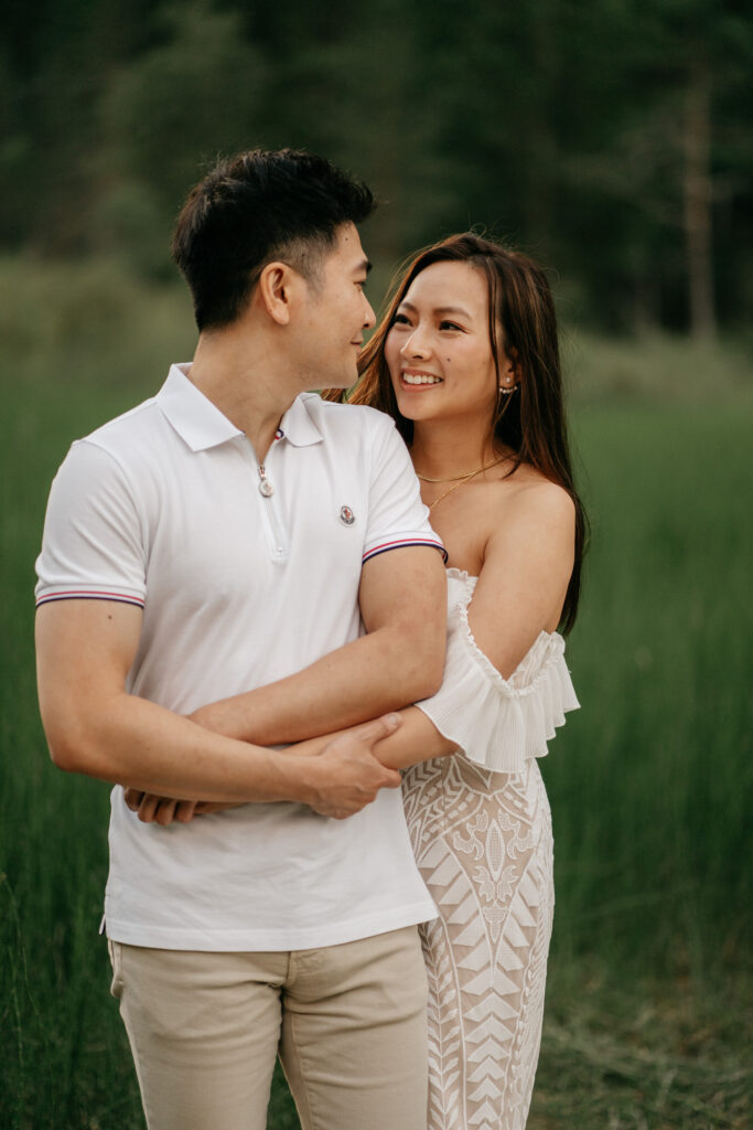 Couple smiling and embracing in green field.