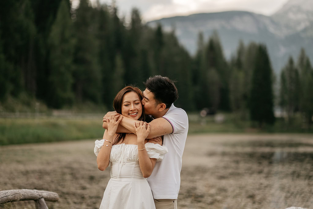 Couple hugging outdoors with forest backdrop