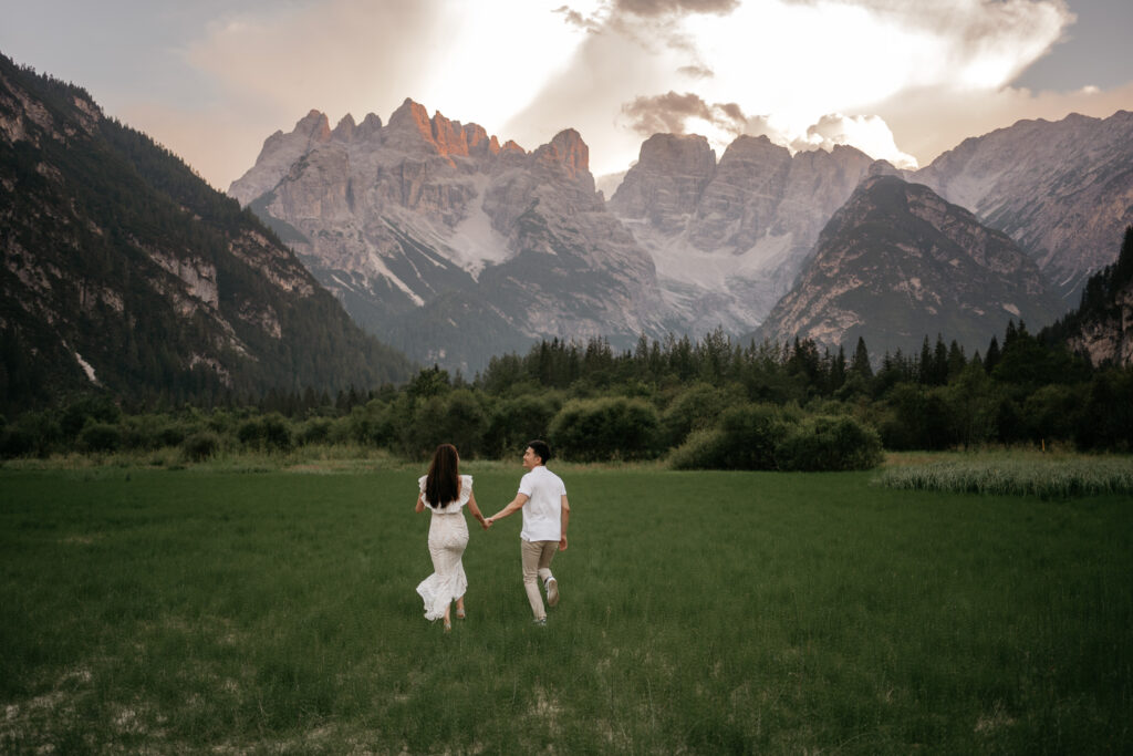 Couple runs towards mountains at sunset.