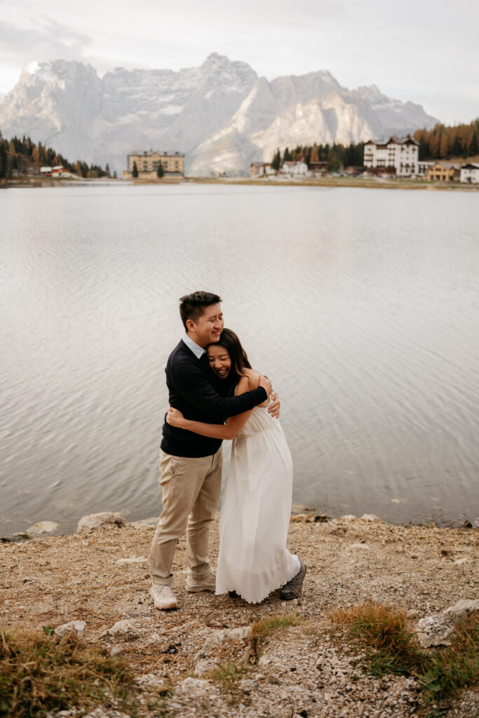 Couple hugging by a mountain lake.