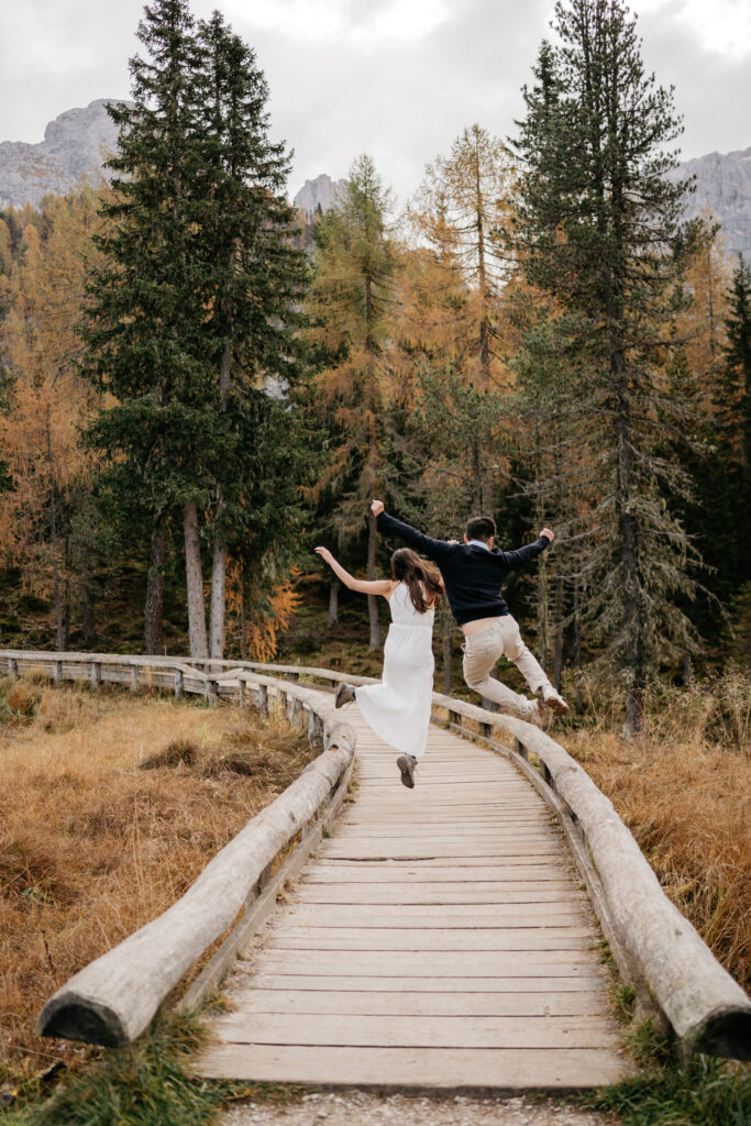 Couple jumping on forest path in autumn