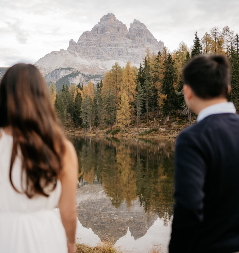 Couple gazing at mountain reflection in calm lake.