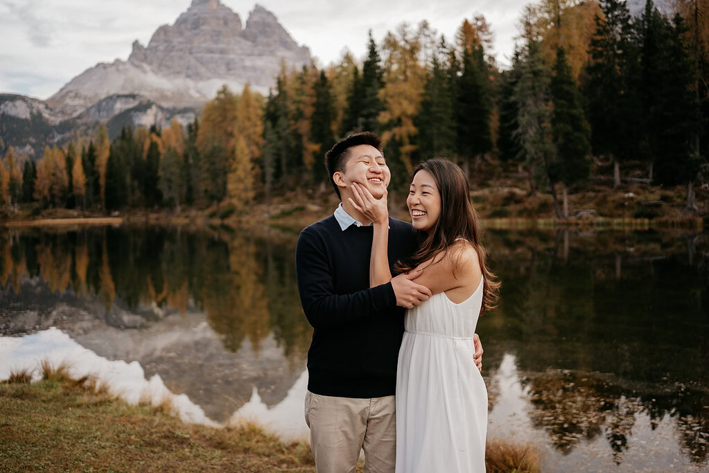 Couple smiling by a scenic lake view.