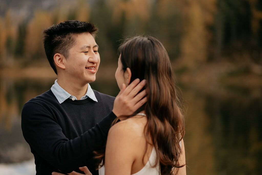 Couple smiling by a lake in autumn.