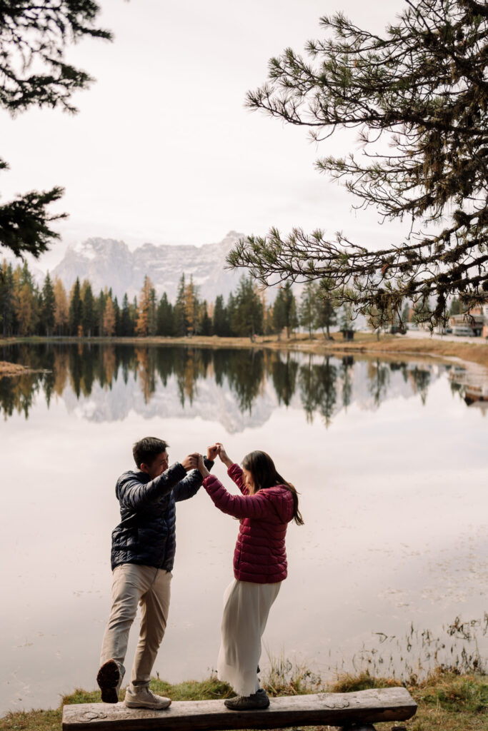 Couple dancing by a serene lake and mountains.