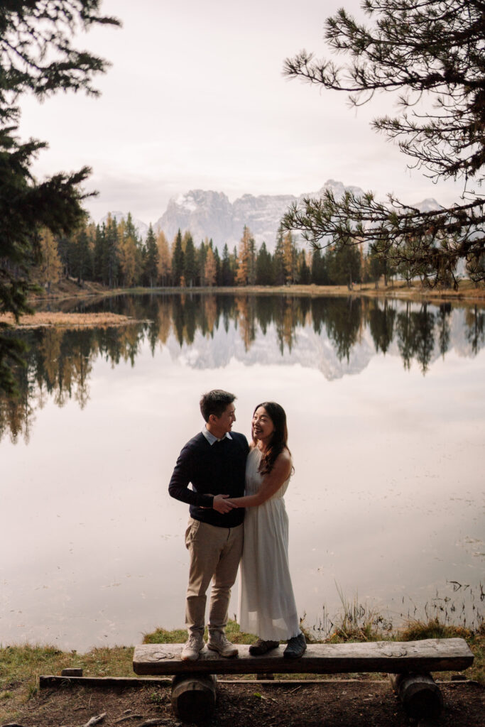 Couple embracing by a scenic lake and mountains.