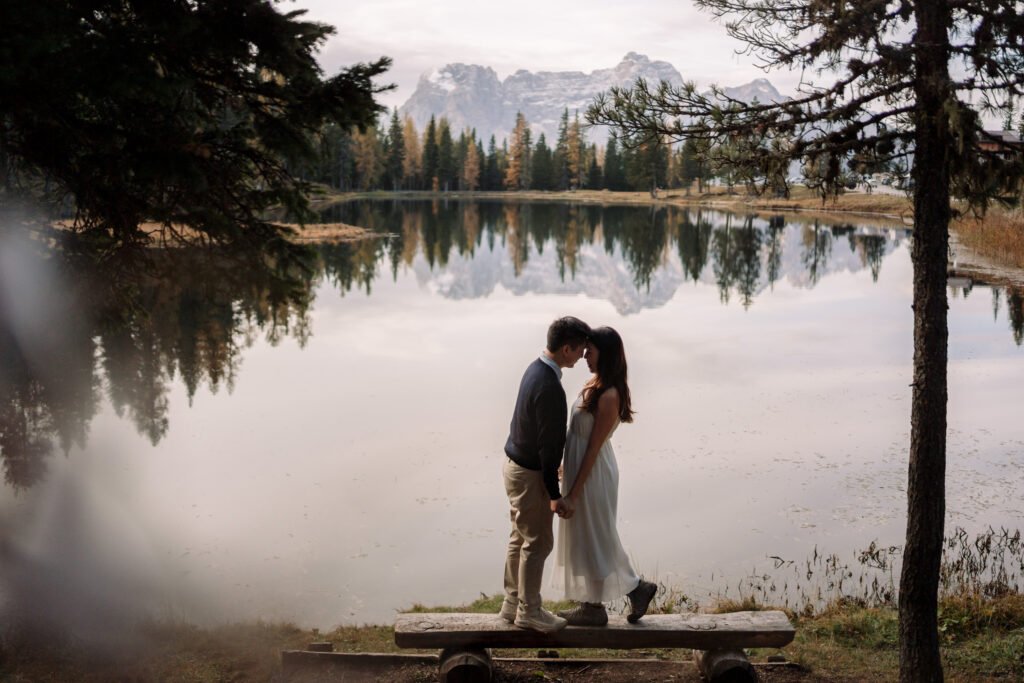 Couple kissing by a serene mountain lake.