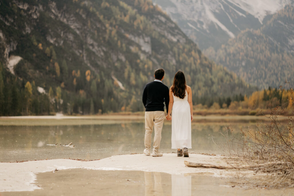 Couple holding hands by a scenic lake.