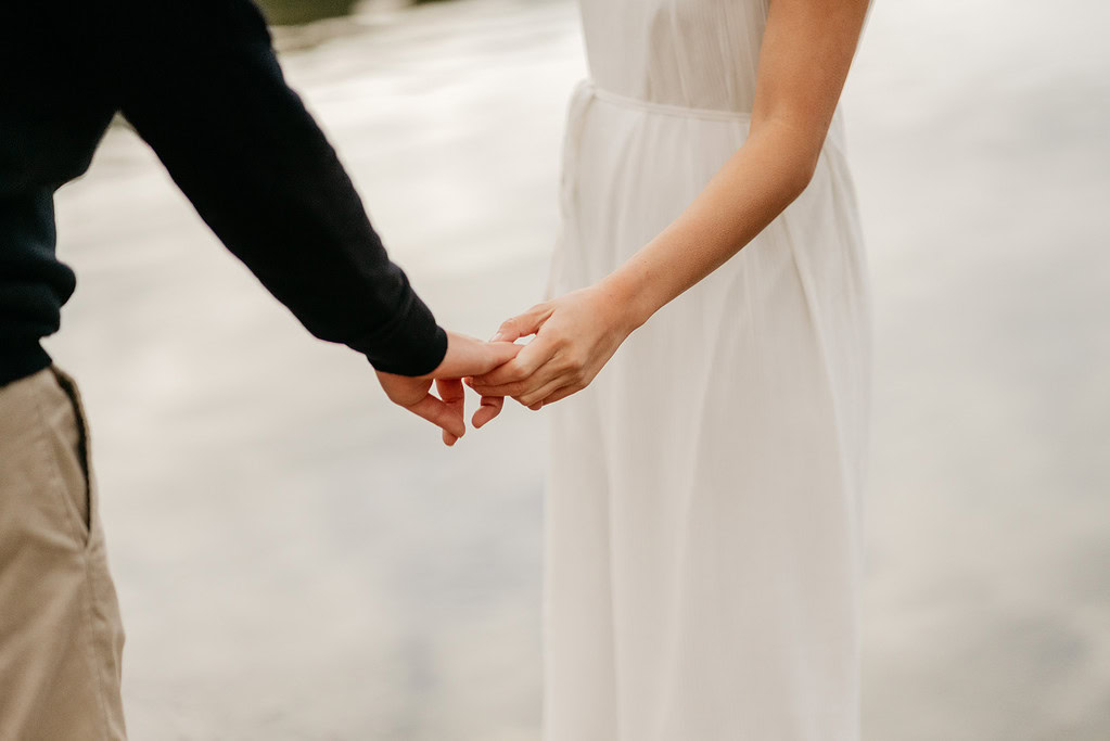 Couple holding hands outdoors in romantic setting.